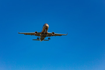 Passenger plane flying in the blue sky in sunlight rays