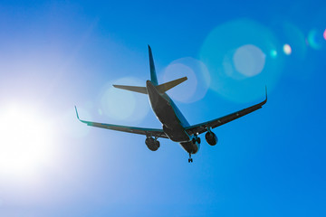 Passenger plane flying in the blue sky in sunlight rays