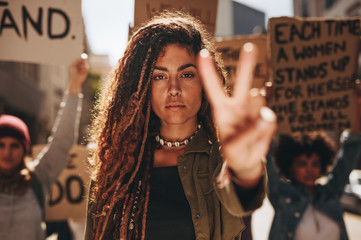 Woman showing a peace sign during protest - obrazy, fototapety, plakaty