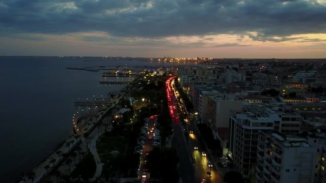 Aerial drone shot flying over a busy street at night with city lights of Limassol Cyprus