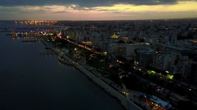 Aerial drone shot over the coast of Limassol city at night with city lights