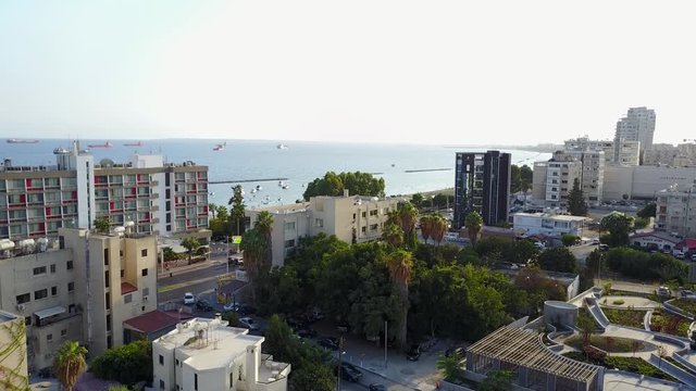 Aerial drone shot pulling back from the shore into the mainland of Limassol City, Cyprus