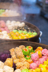Dim Sum at a food stall in different colorful variations, ready for sale.