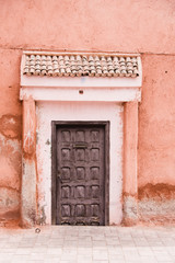 Fototapeta na wymiar Old Wooden Door with Terracotta Pink Stone Wall, Marrakech, Morocco