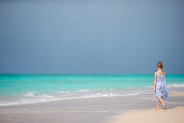 Beautiful little girl in dress at beach having fun.