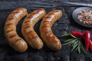 Grilled sausages on a black background of charcoal. Barbecue grill