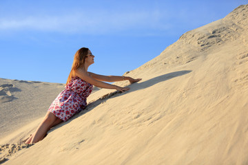 Piękna rudowłosa dziewczyna wypoczywa na piaszczystych wydmach.