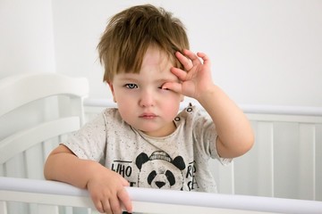 Sleepy child in the bed waking up or getting sleep.