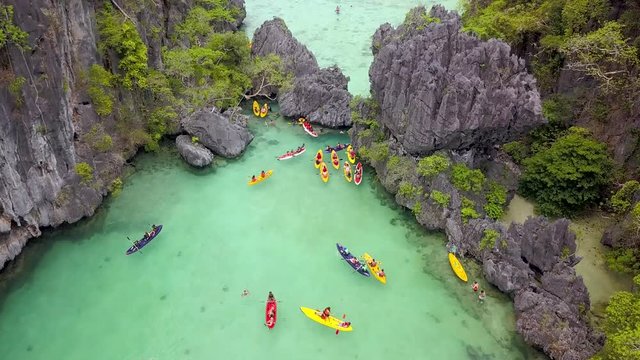 Sea kayaks in a narrow, ocean filled canyon surrounded by towering cliffs