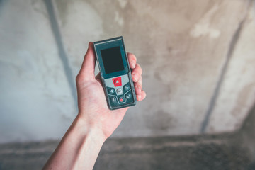 Hand holding construction roulette, calliper and laser range finder on wall background. Laser measuring tool.