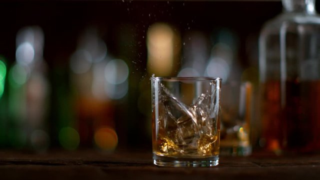 Ice dropped into glass of whisky in super slow motion. Shot with high speed cinema camera Phantom VEO 4K , 1000fps.