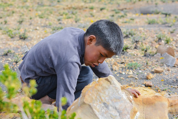 Native american boy bended and looking for something.