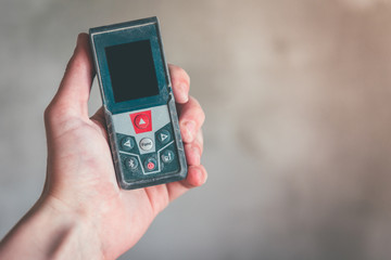 Hand holding construction roulette, calliper and laser range finder on wall background. Laser measuring tool.