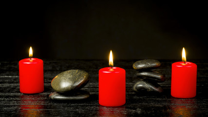 Red candles with black stones on a dark background