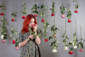 Girl with red hair among hanging roses
