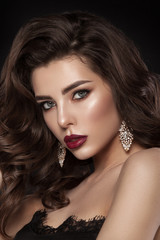 Fototapeta premium Fashion glamorous portrait of a girl on a dark background. Elegant hairstyle, bright makeup and lip color. Hollywood picture.