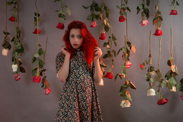Girl with red hair among hanging roses