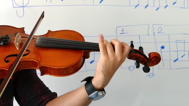 Violinist playing the violin at the school, teaches notes,classic turkish music.
