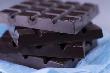 Square stick of chocolate on blue paper. Handmade.