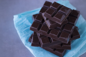 Square stick of chocolate on blue paper. Handmade.