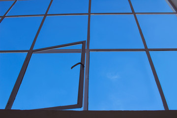 Blue sky view through loft transparent window with open leaf