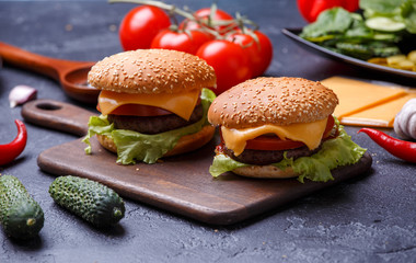 Image of two hamburgers on wooden board, cheese