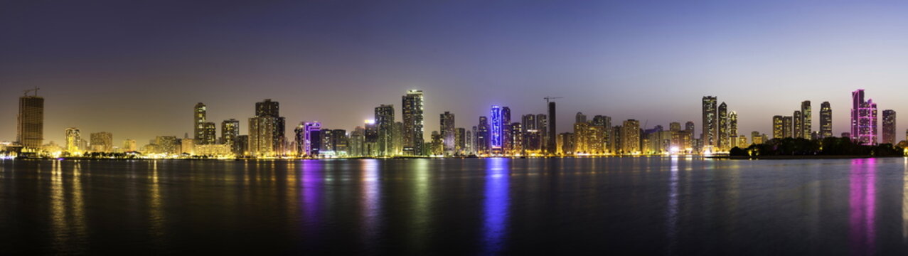 Panoramic view of Sharjah waterfront cityscape in UAE at dusk
