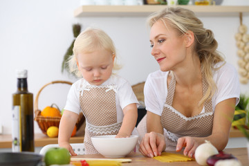 Mother and little daughter  cooking in the kitchen. Spending time all together or happy family concept