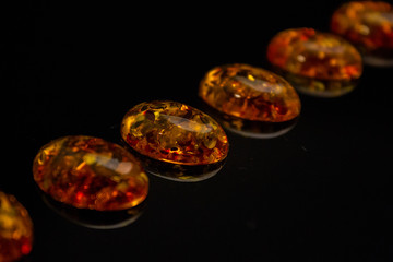 Obraz na płótnie Canvas Artificial amber cabochons on a black background macro