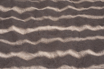 Sandy texture. Summer background. Patterns from the sun and shadows on sand