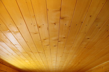 The ceiling in the house of pine boards. The boards are covered with a protective layer. Background. Texture.