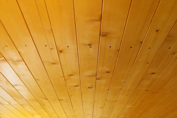 The ceiling in the house of pine boards. The boards are covered with a protective layer. Background. Texture.