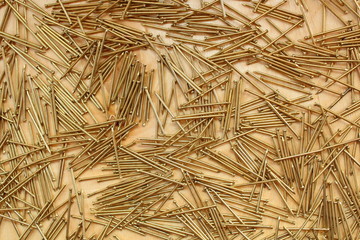 Small furniture nails of golden color on a sheet of plywood. Texture. Background.