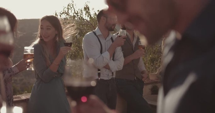 Young multi-ethnic friends drinking wine and beer at rustic party