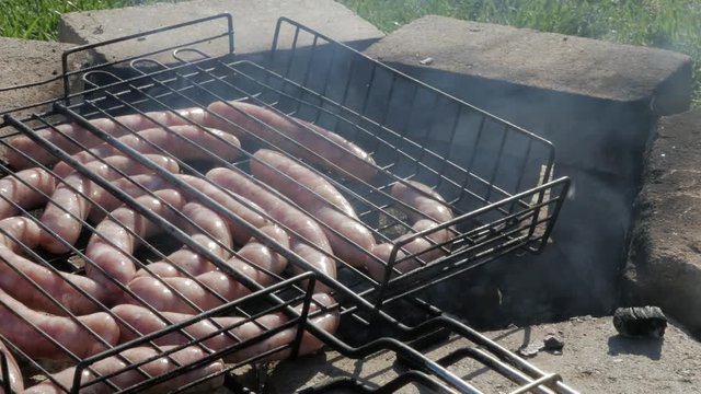 White sausages grilling on the barbeque close up.