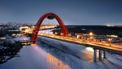 Obraz premium Flying around the Picturesque Bridge over the Moskva river at dusk. Aerial dolly shot of the intense traffic on the illuminated bridge over the frozen river.