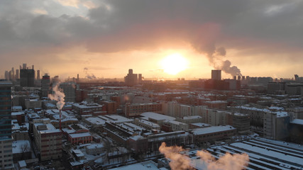 Smooth aerial shot around industrial factory chimney, dense fume comes out of the plant pipe, air pollution sunset scene.