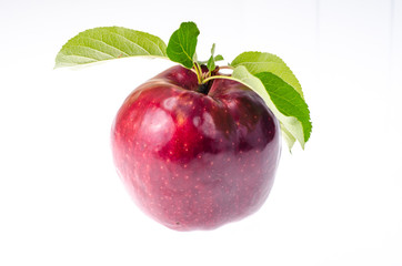 Single red ripe sweet apple with green leaves