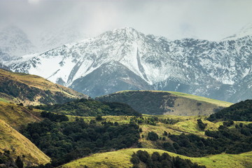 Snow covered mountains and green rolling hills of New Zealand
