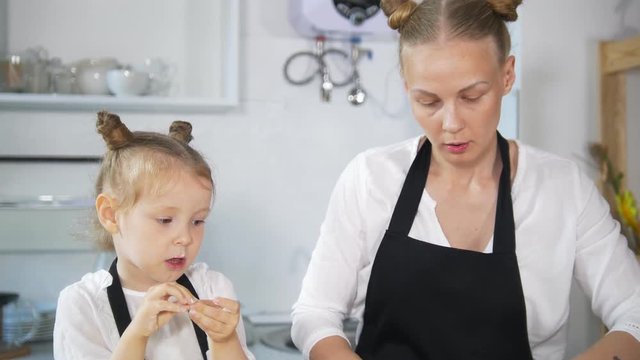 Young mother with her little daughter preparing cottage cheese pancakes together