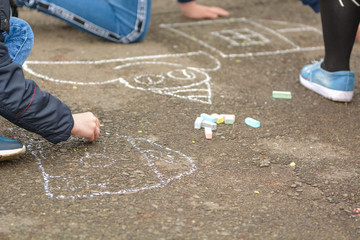 Children paint chalk on the asphalt.