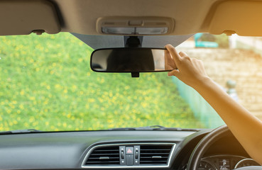 Hand woman using rear view mirror in the car,Transportation and vehicle safety concept,Selective...