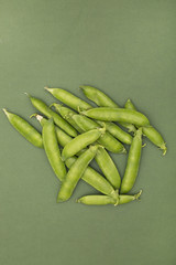 Green pea pods on a green background