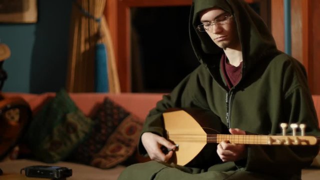 Closeup of Turkish baglama saz musician recording music into a digital recorder.