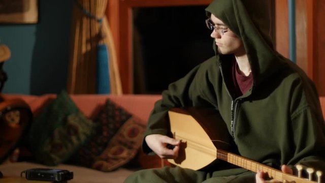 Turkish baglama saz musician recording music into a digital recorder.