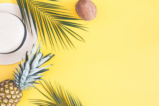 Summer composition. Tropical palm leaves, hat, pineapple, coconut on yellow background. Summer concept. Flat lay, top view, copy space