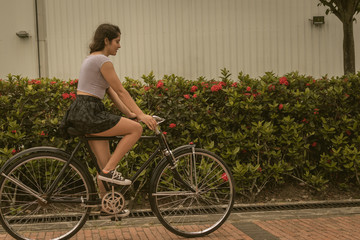chica montando en un sendero de rosas en una bicicleta vieja