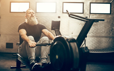 Mature man exercising on a rowing machine at the gym