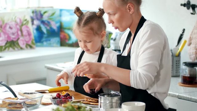 Mom and little girl preparing the decoration for food with fruit