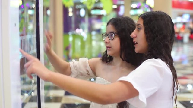 Two girls use the interactive panel in the mall. girls choose the goods with the help of an interactive panel.